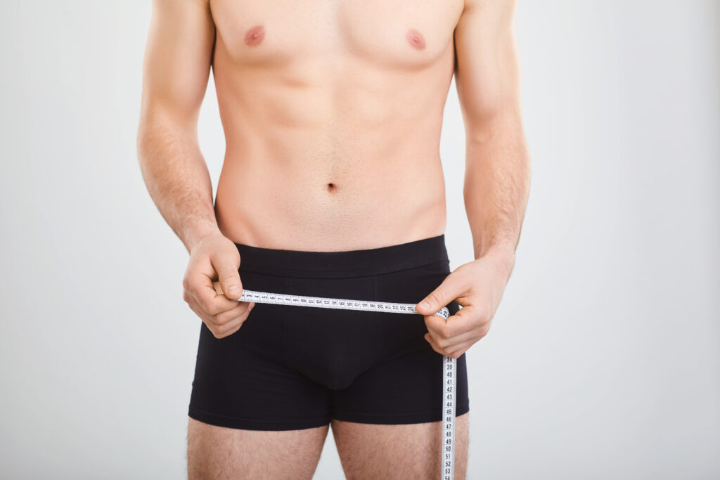 man in boxer shorts holding a measuring tape