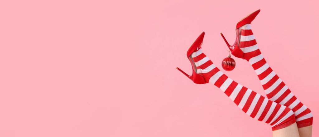 women's legs with striped red and white socks, red heels and a Christmas decoration. 