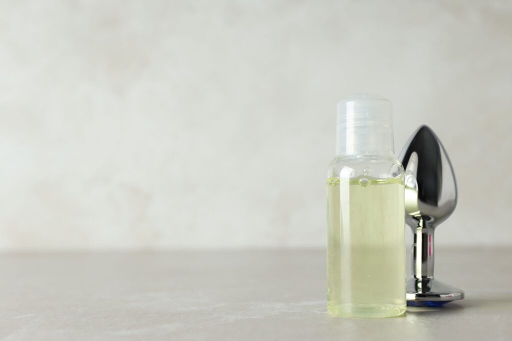 A bottle of lubricant next to a metal puttplug