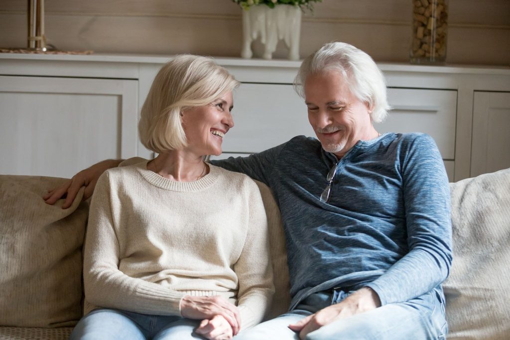 An older couple sitting on the sofa and laughing